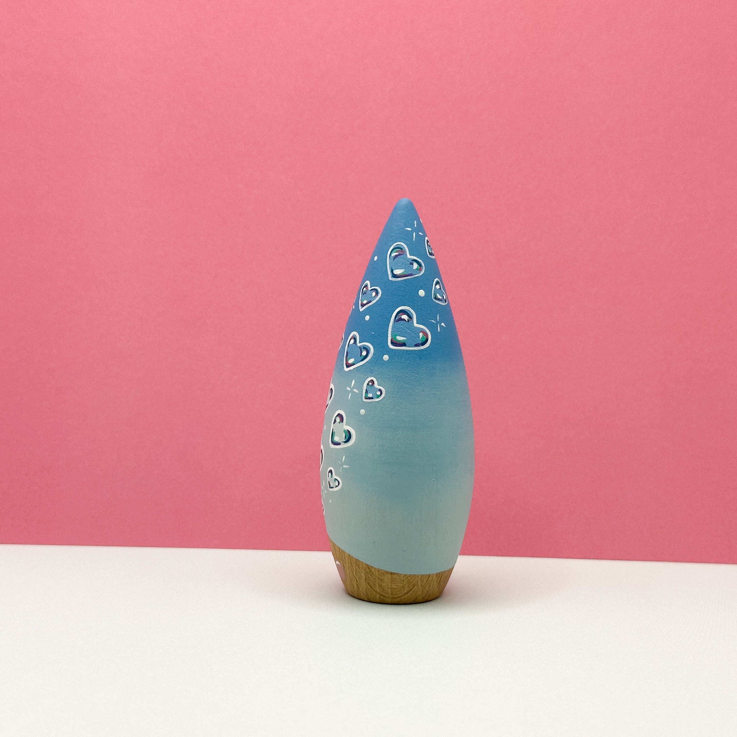 Blue decorative object with heart patterns on a pink background