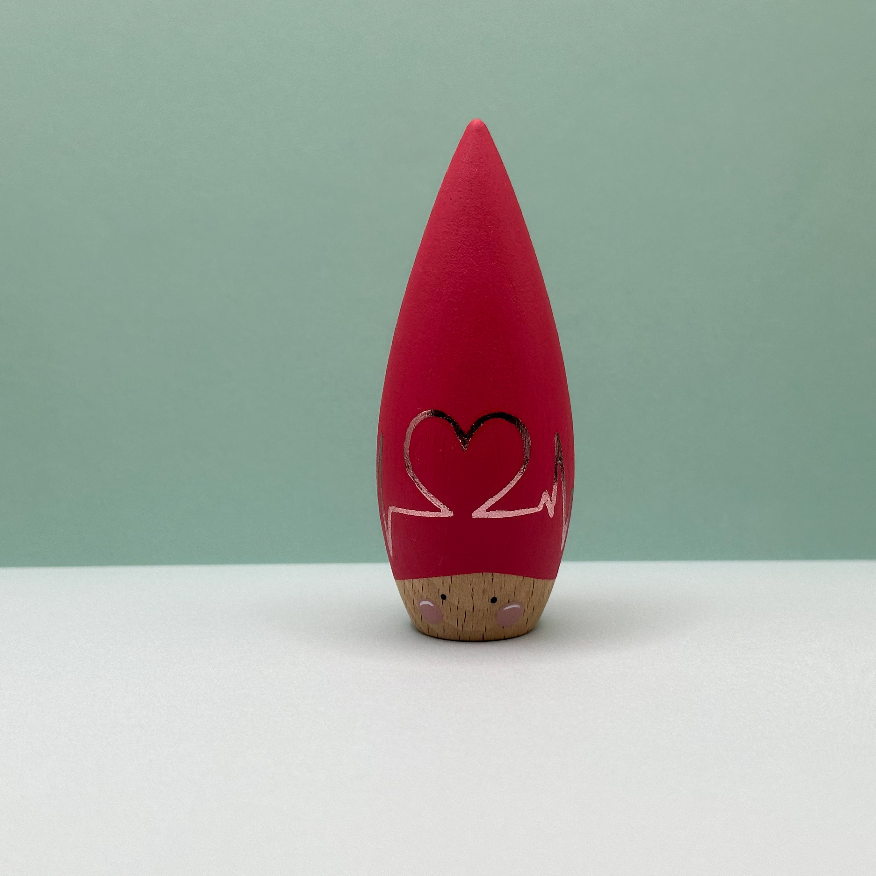 Red heart-shaped object with a pink line design on a light green background