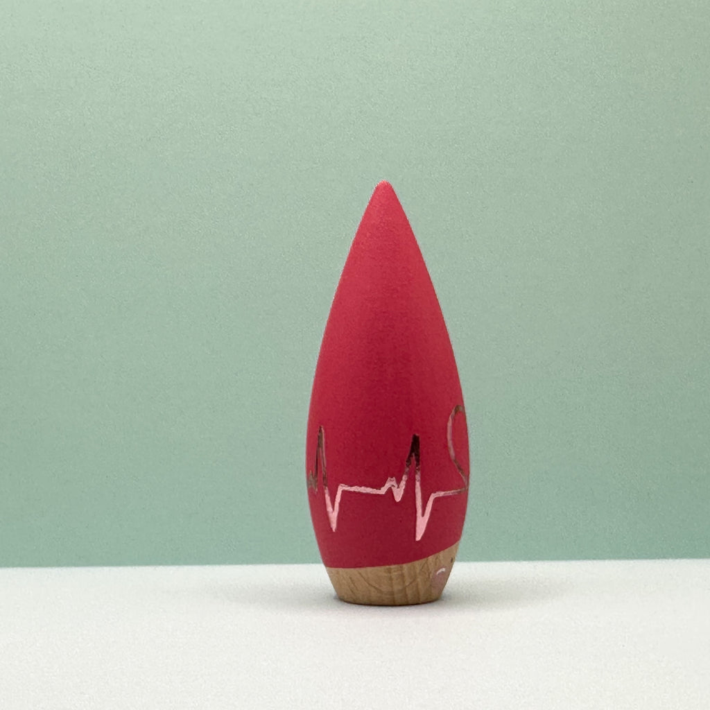 Red wooden toy with a face on a light green background